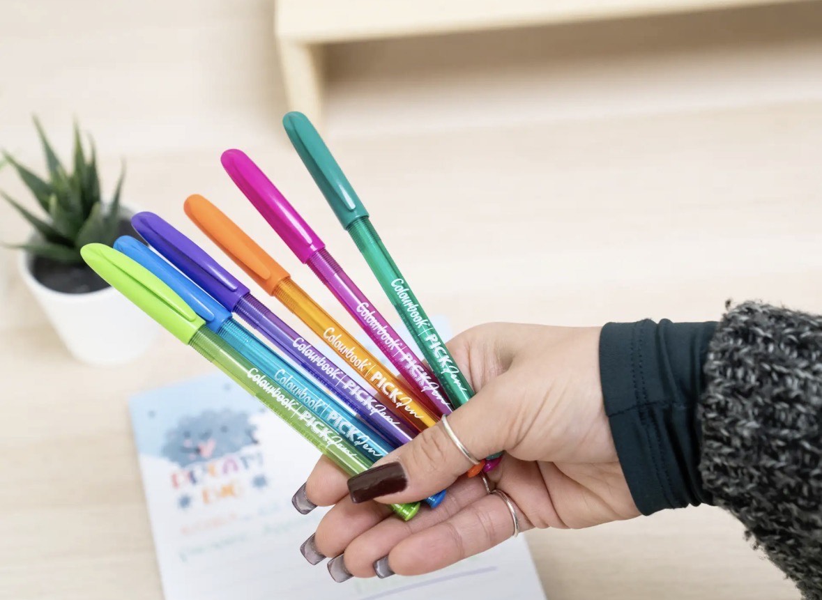 Mano che tiene set di penne a sfera Pick Pen Colourbook colorate con inchiostro brillante